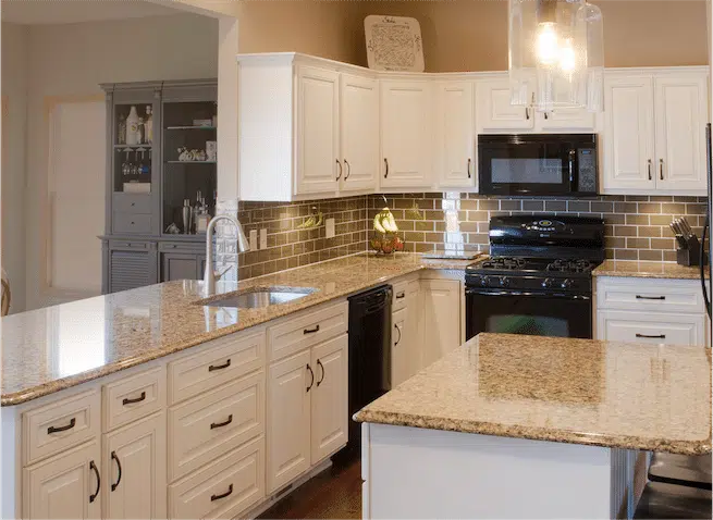 Image of a kitchen with new custom cabinets and countertop, featuring a white farmhouse sink and stainless steel appliances.